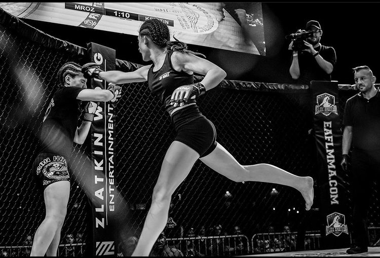 Black and white photo of Brianna Kristin throwing a knee in the cage