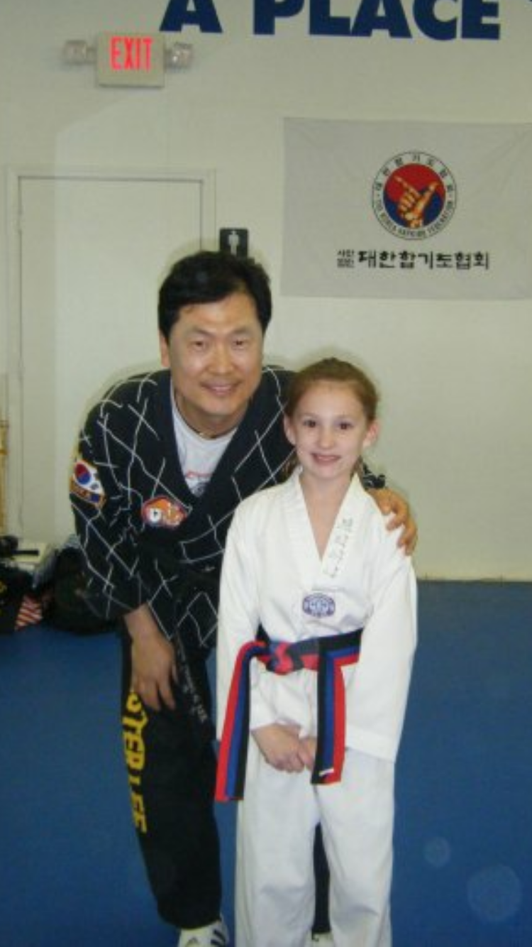 Young Brianna Kristin with her Taekwondo instructor and a trophy