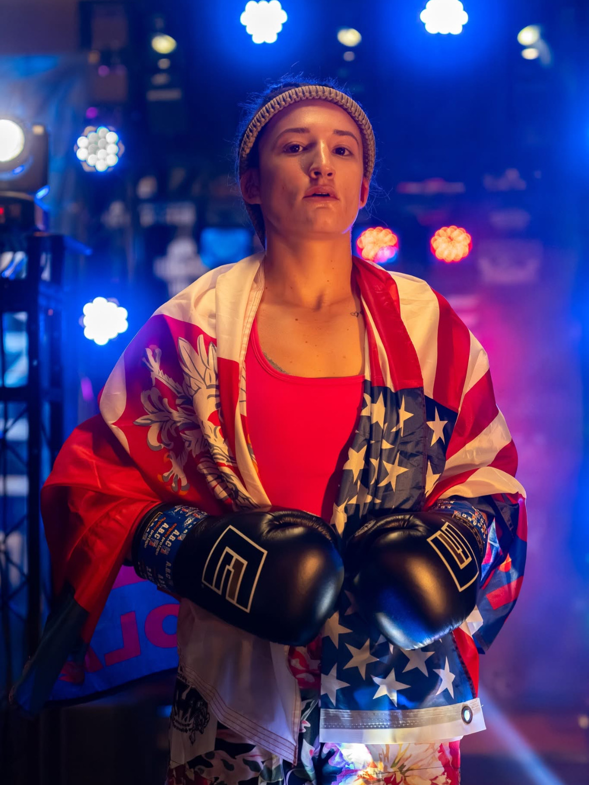 Brianna "The Pitbull" Kristin wrapped in the American flag, gloves raised, ringside.